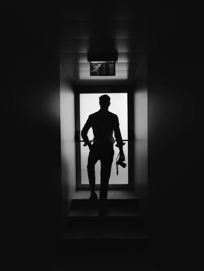 Silhueta de um homem numa porta, ao fundo de um corredor escuro